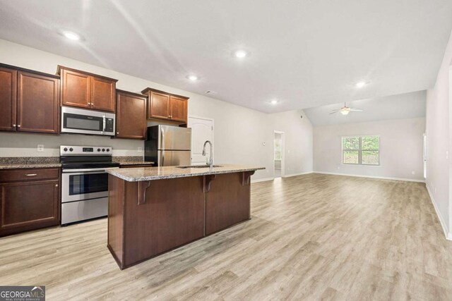 175 Orchard Ln, Covington, GA 30014 - kitchen with appliances with stainless steel finishes, a sink, a ceiling fan, light stone countertops, and a breakfast bar area