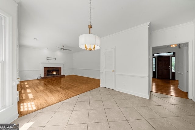 10865 Misty Moon Ct, Alpharetta, GA 30022 - unfurnished living room with a ceiling fan, light tile patterned flooring, crown molding, a brick fireplace, and baseboards
