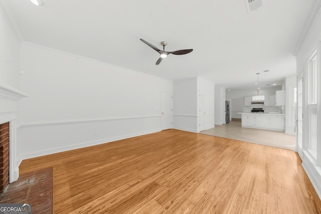 10865 Misty Moon Ct, Alpharetta, GA 30022 - unfurnished living room with a brick fireplace, ceiling fan, light wood-style floors, a sink, and crown molding