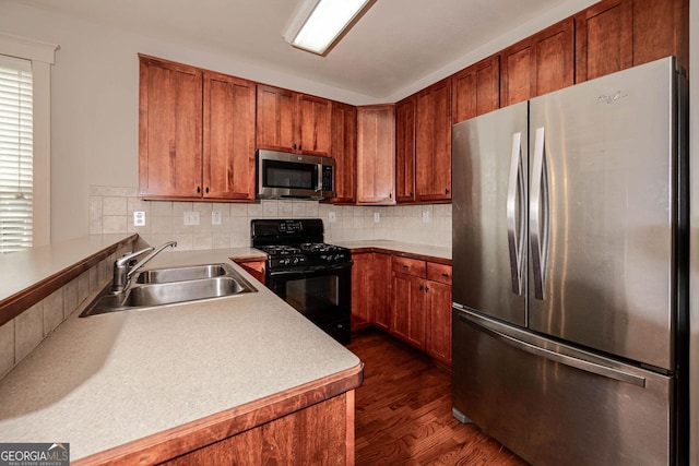 65 Orchard Dr, Covington, GA 30014 - kitchen with stainless steel appliances, a sink, dark wood-style flooring, tasteful backsplash, and brown cabinetry