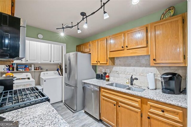 202 Berkeley Woods Dr, Duluth, GA 30096 - kitchen featuring a sink, appliances with stainless steel finishes, washer and clothes dryer, tasteful backsplash, and light stone countertops
