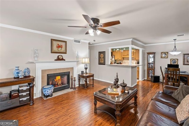 202 Berkeley Woods Dr, Duluth, GA 30096 - living area featuring a ceiling fan, wood finished floors, a tiled fireplace, crown molding, and baseboards