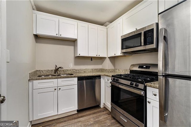 2576 Godfrey Dr, Atlanta, GA 30318 - kitchen with stainless steel appliances, a sink, white cabinets, and wood finished floors