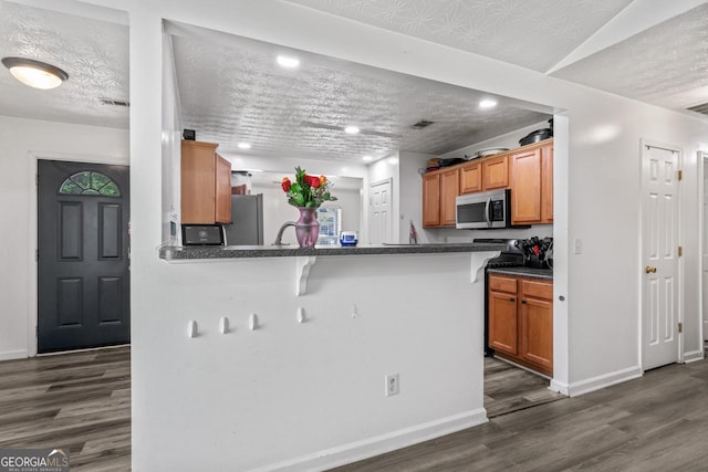 11581 Kades Trl, Hampton, GA 30228 - kitchen featuring appliances with stainless steel finishes, dark wood-style floors, dark countertops, baseboards, and a textured ceiling