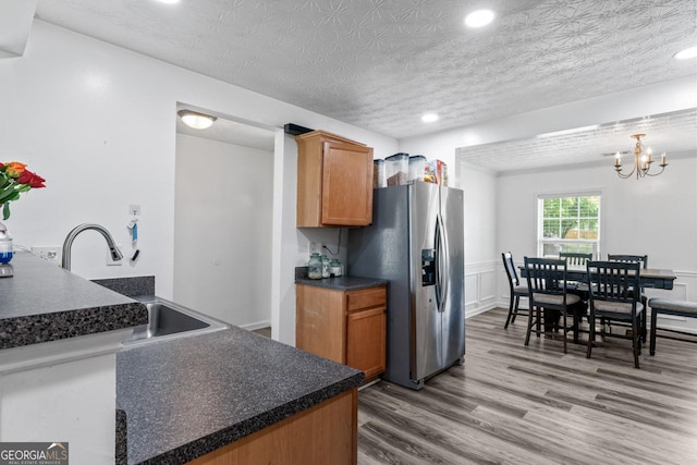 11581 Kades Trl, Hampton, GA 30228 - kitchen featuring stainless steel fridge, a sink, dark countertops, wood finished floors, and brown cabinets