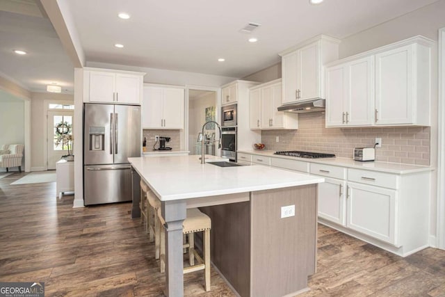 7345 Vale Ct, Cumming, GA 30028 - kitchen featuring appliances with stainless steel finishes, a sink, under cabinet range hood, dark wood-style floors, and tasteful backsplash
