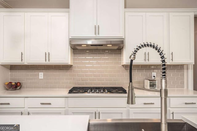 7345 Vale Ct, Cumming, GA 30028 - kitchen with under cabinet range hood, white cabinets, tasteful backsplash, and light countertops