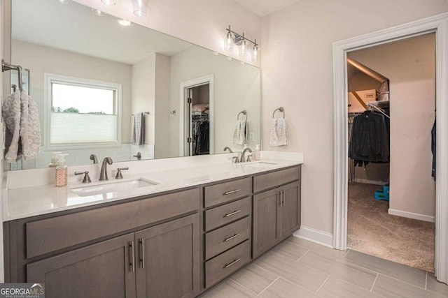 7345 Vale Ct, Cumming, GA 30028 - bathroom featuring double vanity, a walk in closet, and baseboards