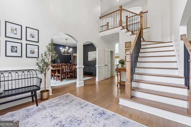 712 Brookshade Pkwy, Alpharetta, GA 30004 - staircase featuring wood finished floors, a towering ceiling, a chandelier, arched walkways, and a decorative wall