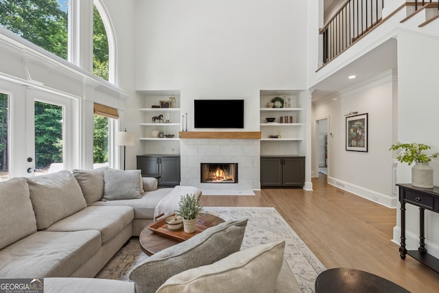 712 Brookshade Pkwy, Alpharetta, GA 30004 - living room featuring a towering ceiling, a fireplace, baseboards, light wood-style flooring, and built in features