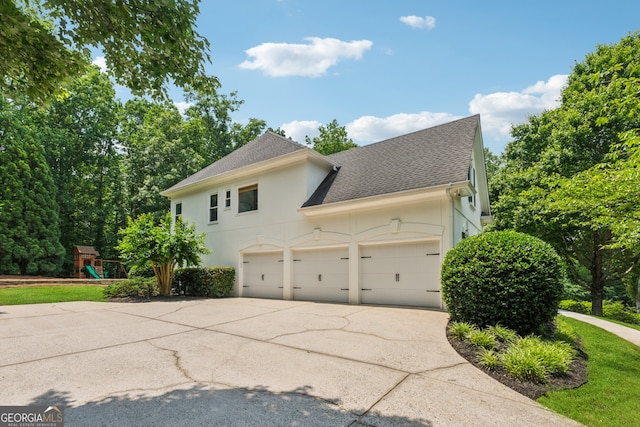 712 Brookshade Pkwy, Alpharetta, GA 30004 - view of side of home with a shingled roof, concrete driveway, stucco siding, an attached garage, and a playground