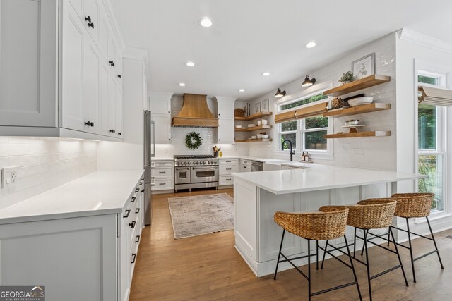 712 Brookshade Pkwy, Alpharetta, GA 30004 - kitchen featuring stainless steel appliances, open shelves, custom exhaust hood, a peninsula, and decorative backsplash