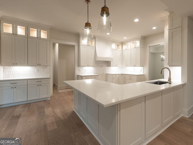 4955 Chamblee Dunwoody Rd, Dunwoody, GA 30338 - kitchen featuring premium range hood, a peninsula, wood finished floors, tasteful backsplash, and recessed lighting