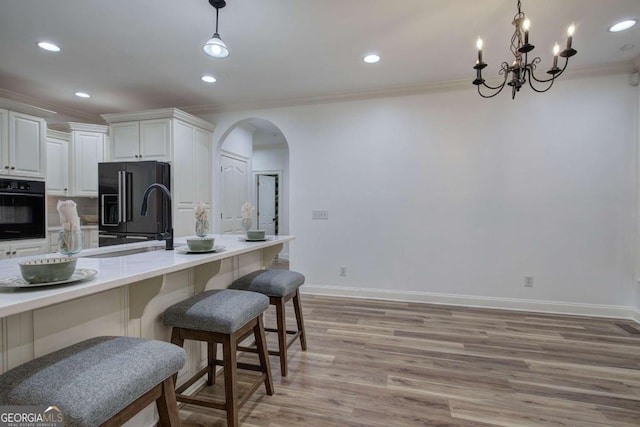 1488 Pleasant Hill Rd NE, Ranger, GA 30734 - kitchen featuring black appliances, ornamental molding, arched walkways, light wood-style flooring, and white cabinetry