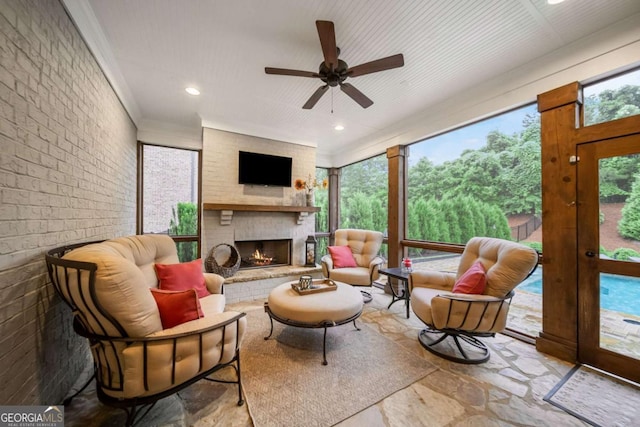 2377 Kesgrove Way, Buford, GA 30518 - living area with stone flooring, a fireplace, a ceiling fan, brick wall, and ornamental molding