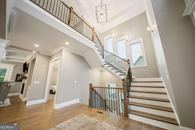 2377 Kesgrove Way, Buford, GA 30518 - staircase featuring wood finished floors, a chandelier, ornamental molding, recessed lighting, and a towering ceiling