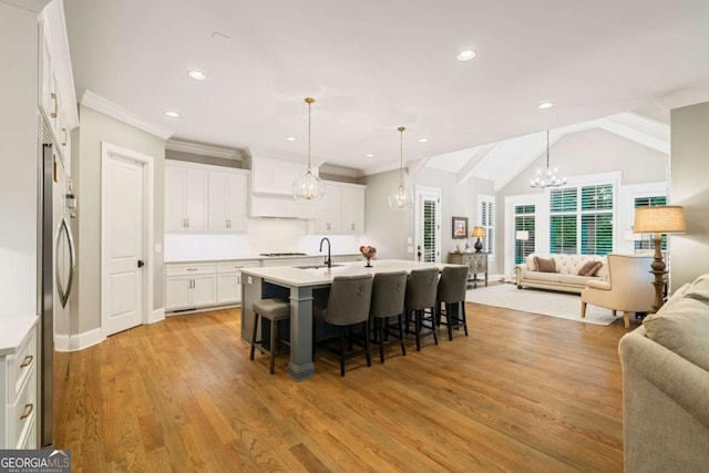 2377 Kesgrove Way, Buford, GA 30518 - kitchen with open floor plan, a chandelier, a kitchen breakfast bar, light wood finished floors, and white cabinetry