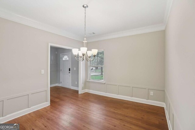 4546 Water Mill Dr, Buford, GA 30519 - empty room featuring a chandelier, ornamental molding, a decorative wall, wood finished floors, and wainscoting
