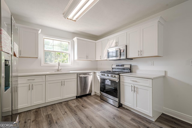 2576 Abbotts Glen Dr NW, Acworth, GA 30101 - kitchen with stainless steel appliances, a sink, light wood-type flooring, and white cabinets