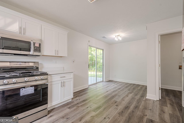 2576 Abbotts Glen Dr NW, Acworth, GA 30101 - kitchen with stainless steel appliances, light wood-style flooring, baseboards, white cabinets, and light countertops