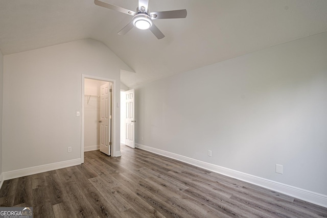 2576 Abbotts Glen Dr NW, Acworth, GA 30101 - unfurnished bedroom with dark wood-style flooring, lofted ceiling, baseboards, a ceiling fan, and a walk in closet