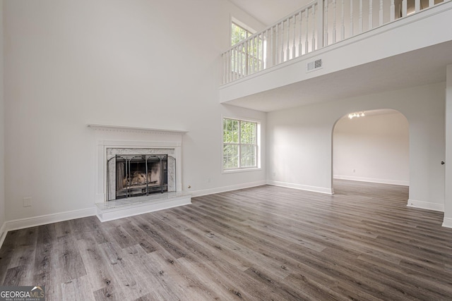 2576 Abbotts Glen Dr NW, Acworth, GA 30101 - unfurnished living room featuring a high ceiling, wood finished floors, arched walkways, baseboards, and a fireplace