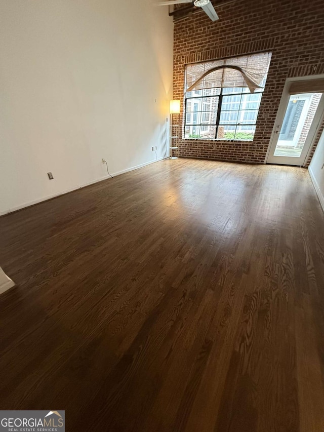 320 Martin Luther King Jr Dr SE Unit 5, Atlanta, GA 30312 - unfurnished living room with brick wall, dark wood-style flooring, and baseboards