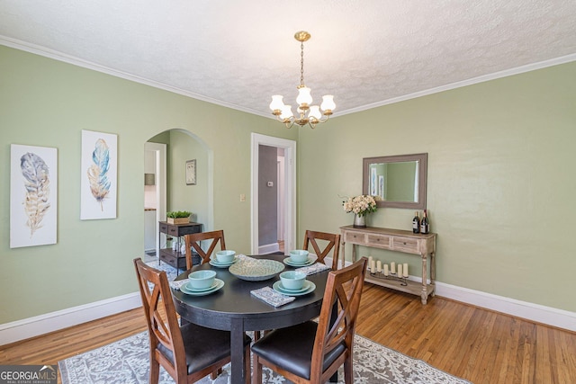 1391 Jefferson Ave, East Point, GA 30344 - dining area with arched walkways, a chandelier, wood finished floors, baseboards, and crown molding
