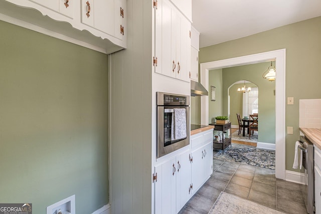 1391 Jefferson Ave, East Point, GA 30344 - kitchen with stainless steel appliances, under cabinet range hood, white cabinets, a chandelier, and baseboards