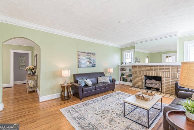 1391 Jefferson Ave, East Point, GA 30344 - living area with a fireplace, arched walkways, ornamental molding, light wood-style floors, and a textured ceiling