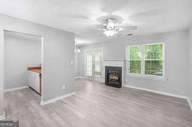 6947 Gallant Cir Unit 10, Mableton, GA 30126 - unfurnished living room with a ceiling fan, light wood-style floors, a fireplace with flush hearth, a textured ceiling, and baseboards