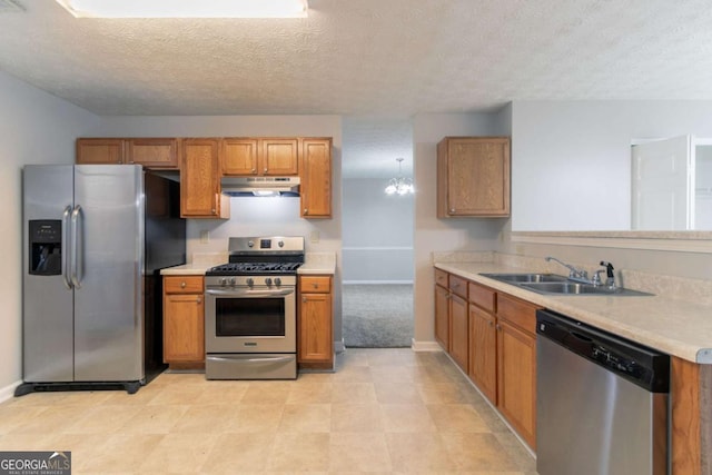 2191 Phillips Rd, Lithonia, GA 30058 - kitchen with appliances with stainless steel finishes, under cabinet range hood, a textured ceiling, light countertops, and brown cabinetry