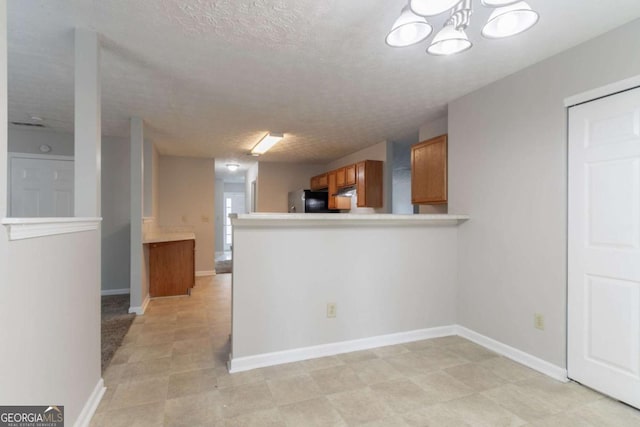 2191 Phillips Rd, Lithonia, GA 30058 - kitchen with fridge, brown cabinetry, a textured ceiling, light countertops, and a chandelier