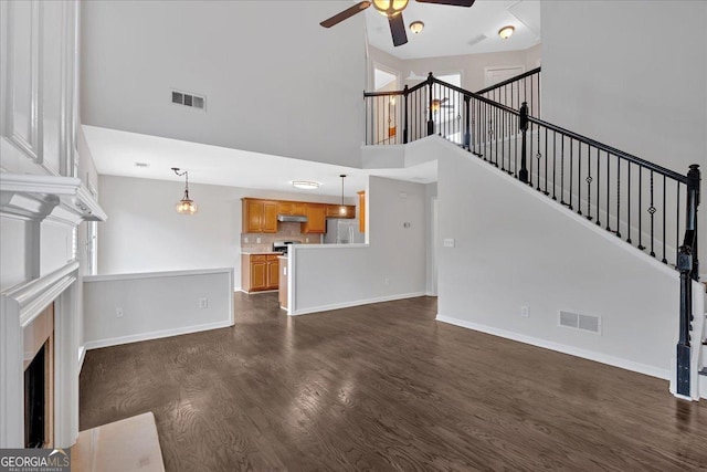535 Watercress Dr, Woodstock, GA 30188 - unfurnished living room featuring ceiling fan, dark wood-style floors, a towering ceiling, baseboards, and stairway