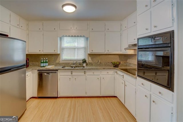 2808 Peeler Rd, Dunwoody, GA 30360 - kitchen with black appliances, light wood-style flooring, white cabinets, and under cabinet range hood