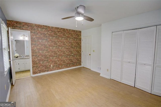 2808 Peeler Rd, Dunwoody, GA 30360 - unfurnished bedroom featuring brick wall, light wood-style flooring, a closet, baseboards, and connected bathroom
