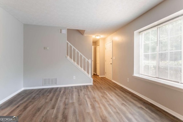 5092 Stone Trce, Stone Mountain, GA 30083 - unfurnished living room featuring stairs, wood finished floors, a textured ceiling, and baseboards