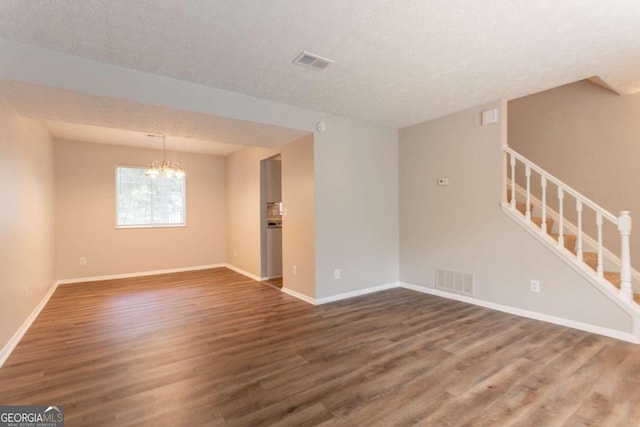 5092 Stone Trce, Stone Mountain, GA 30083 - empty room with wood finished floors, a textured ceiling, a chandelier, stairs, and baseboards