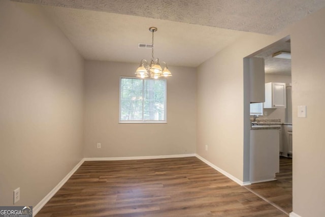 5092 Stone Trce, Stone Mountain, GA 30083 - unfurnished dining area featuring dark wood finished floors, a chandelier, baseboards, and a textured ceiling
