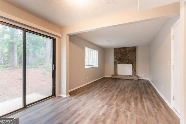 5092 Stone Trce, Stone Mountain, GA 30083 - unfurnished living room featuring wood finished floors, a fireplace, baseboards, and a textured ceiling