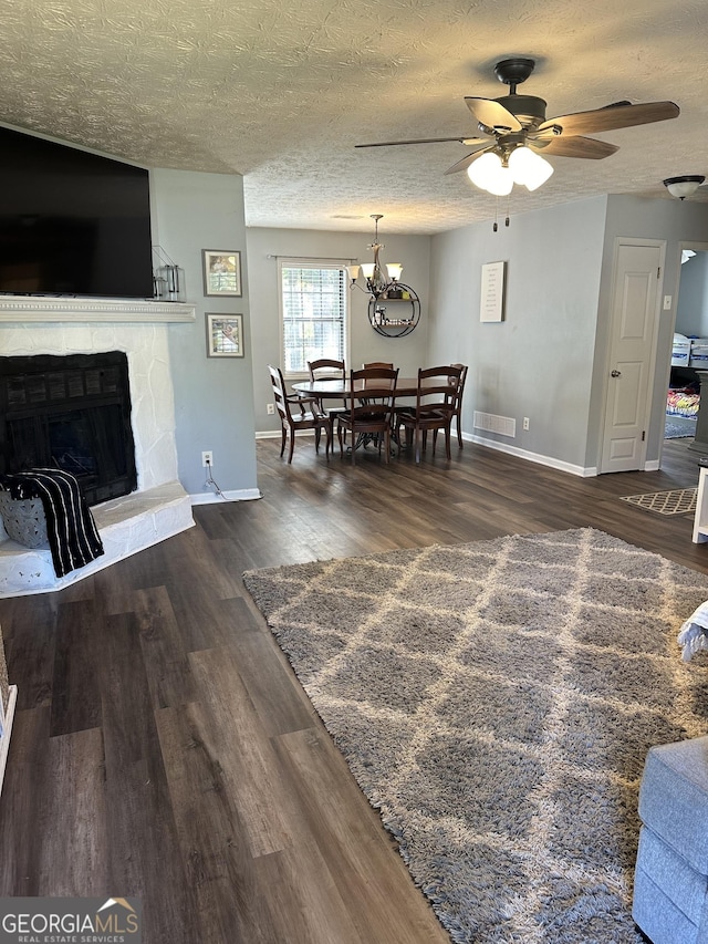 517 Pebble Pt, Loganville, GA 30052 - dining space featuring a fireplace, ceiling fan, dark wood finished floors, baseboards, and a textured ceiling