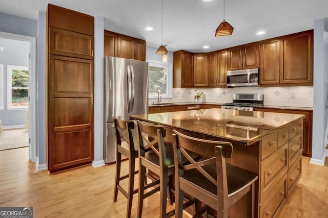 4794 Glenbonnie Ct, Dunwoody, GA 30360 - kitchen featuring appliances with stainless steel finishes, decorative backsplash, dark stone countertops, light wood-style flooring, and decorative light fixtures