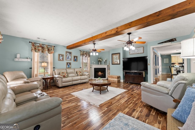 8958 Bill Savage Rd, Lula, GA 30554 - living room featuring plenty of natural light, ceiling fan, wood finished floors, a warm lit fireplace, and beamed ceiling