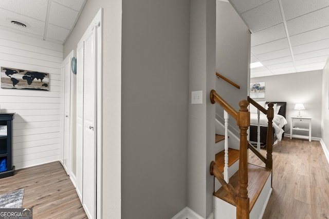 8958 Bill Savage Rd, Lula, GA 30554 - hall featuring a paneled ceiling, light wood-style floors, baseboards, wood walls, and stairway