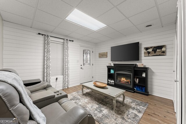8958 Bill Savage Rd, Lula, GA 30554 - living room featuring a drop ceiling, wood finished floors, wooden walls, and a glass covered fireplace