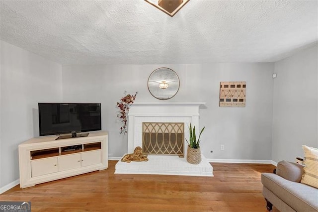 1625 Clark Lake Dr NW, Acworth, GA 30102 - living room with wood finished floors, a brick fireplace, baseboards, and a textured ceiling