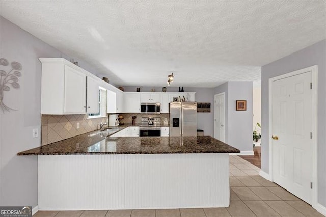 1625 Clark Lake Dr NW, Acworth, GA 30102 - kitchen with appliances with stainless steel finishes, dark stone counters, a peninsula, decorative backsplash, and a sink