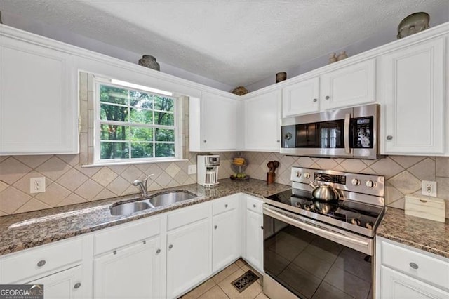1625 Clark Lake Dr NW, Acworth, GA 30102 - kitchen with stainless steel appliances, a sink, white cabinets, dark stone counters, and tasteful backsplash