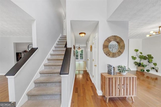 1625 Clark Lake Dr NW, Acworth, GA 30102 - stairway featuring a chandelier, a textured ceiling, wood finished floors, and baseboards