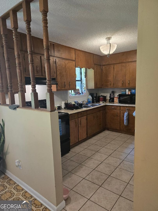 1453 Rose Ln, Toccoa, GA 30577 - kitchen with black appliances, a textured ceiling, light countertops, brown cabinetry, and light tile patterned floors